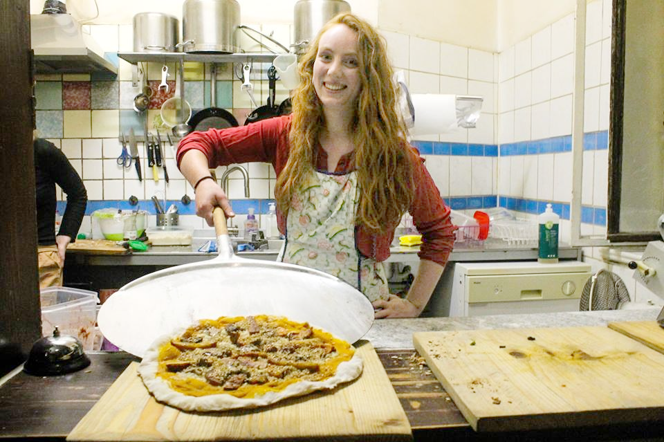 A volunteer is baking Pizza